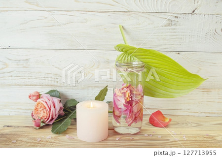 Spa still life with pink fresh roses flowers, candle and rose petal water, on wooden background. Alternative medicine, aromatherapy, body care. Spa still life with pink fresh roses flowers, candle and rose petal water, on wooden background. Alternative medicine, aromatherapy, body care. 127713955