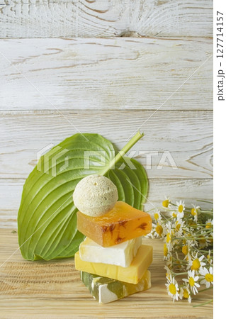 Handmade herbal soap and chamomile flowers on white wooden background. Handmade herbal soap and chamomile flowers on white wooden background. 127714157