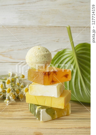 Handmade herbal soap and chamomile flowers on white wooden background. 127714159