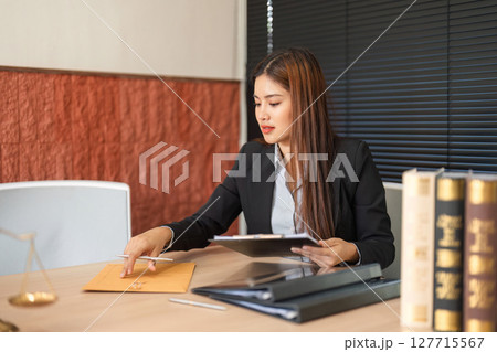 Lawyer and Legal Documents. A dedicated female lawyer reviewing important legal documents at her office desk. Lawyer and Legal Documents. A dedicated female lawyer reviewing important legal documents at her office desk. 127715567