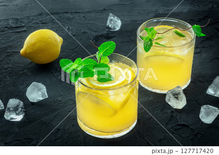 Glasses of lemonade, a mocktail with lemon juice, on a black background Glasses of lemonade, a mocktail with lemon juice, on a black background 127717420