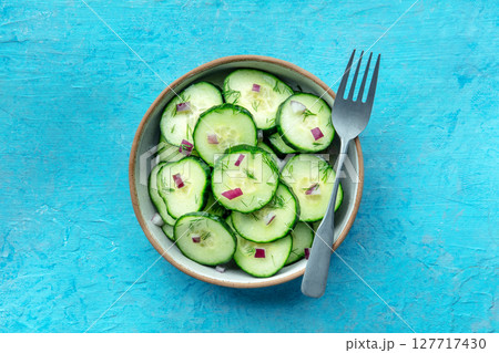 Cucumber salad with olive oil, dill, and red onion, on a blue background 127717430