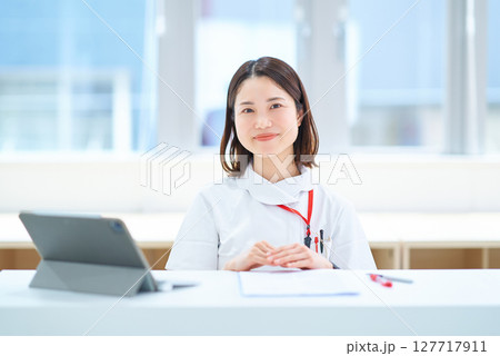 テーブルの前に座る白衣の女性 127717911