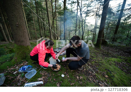 Cooking a delicious meal in the serene woods during a peaceful afternoon getaway surrounded by tall trees and soft mossy ground Cooking a delicious meal in the serene woods during a peaceful afternoon getaway surrounded by tall trees and soft mossy ground 127718306