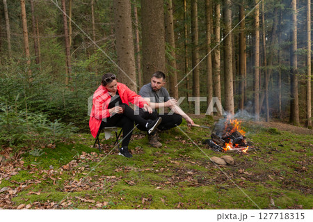 Cozy moments by the fire in the serene woods during an autumn afternoon, sharing stories and savoring the warmth of nature 127718315