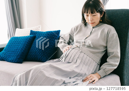 お腹が張って苦しさを感じる妊婦 お腹が張って苦しさを感じる妊婦 127718595