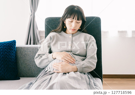 お腹が張って苦しさを感じる妊婦 127718596