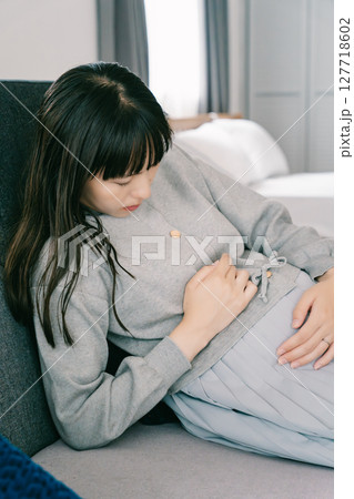お腹が張って苦しさを感じる妊婦 127718602