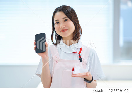 スマートフォンを持つ白衣とエプロン姿の女性 127719160