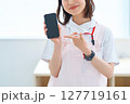 スマートフォンを持つ白衣とエプロン姿の女性 127719161