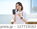 スマートフォンを持つ白衣とエプロン姿の女性 127719162
