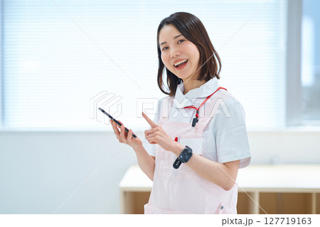 スマートフォンを持つ白衣とエプロン姿の女性 127719163