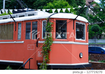 Charming Vintage Tram: A Beautifully Restored Transportation Museum Attraction with Unique Orange Color and Decorative Elements in a Picturesque Outdoor Setting Charming Vintage Tram: A Beautifully Restored Transportation Museum Attraction with Unique Orange Color and Decorative Elements in a Picturesque Outdoor Setting 127719270