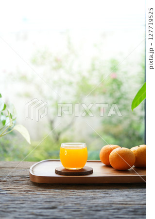 fresh oranges and orange juice on wooden tray by the window 127719525