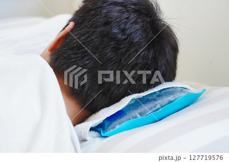 猛暑による熱中症のため、氷枕をしてベッドで休む若い男性 猛暑による熱中症のため、氷枕をしてベッドで休む若い男性 127719576