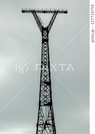 Silhouetted industrial metal tower structure standing tall against gray sky Silhouetted industrial metal tower structure standing tall against gray sky 127719759