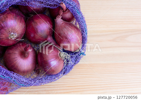 Red Onion In Plastic Mesh Bag Lying On Wooden Background, Harvest Season 127720056