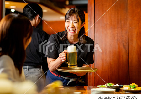 居酒屋で接客をする女性 127720078