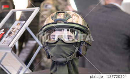 A mannequin wearing a camouflage military helmet exhibits cutting-edge technology designed for combat situations at a defense trade show. 127720394