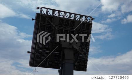 A military radar system stands tall in a warzone, providing surveillance and tracking capabilities amid a backdrop of overcast skies. 127720496