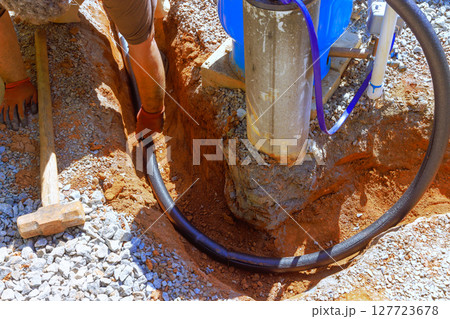 Workers are installing water laying pipe at construction site, digging in ground under works day Workers are installing water laying pipe at construction site, digging in ground under works day 127723678