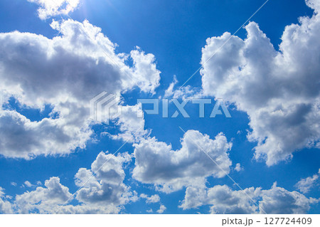 Expansive bright blue sky adorned with fluffy white cumulus clouds, signifying a clear sunny day ideal for outdoor freedom and natural beauty Expansive bright blue sky adorned with fluffy white cumulus clouds, signifying a clear sunny day ideal for outdoor freedom and natural beauty 127724409