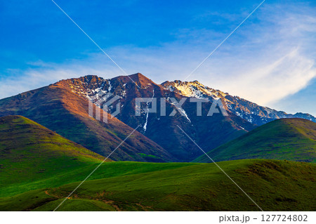 Majestic mountain range with snow-capped peaks and green hills in Kyrgyzstan Majestic mountain range with snow-capped peaks and green hills in Kyrgyzstan 127724802