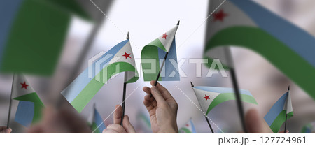 Djibouti flags in their hands on a blurred urban background Djibouti flags in their hands on a blurred urban background 127724961