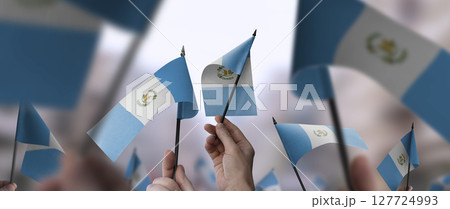 Guatemala flags in their hands on a blurred urban background 127724993