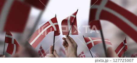 Denmark flags in their hands on a blurred urban background 127725007