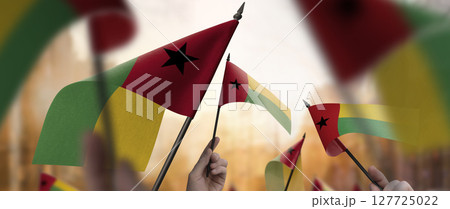 Guinea Bissau flags in their hands on a blurred urban background Guinea Bissau flags in their hands on a blurred urban background 127725022