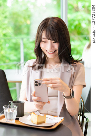 カフェでケーキの写真を撮影する女性 127725804