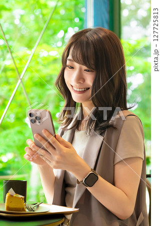 カフェでスマートフォンを使う笑顔の女性 127725813