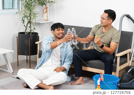 Friendship and Celebration. Two men toasting with water bottles while relaxing at home. 127726708