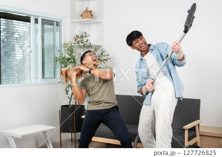 Energetic cleaning session. Friends jamming while vacuuming, creating a fun atmosphere. Energetic cleaning session. Friends jamming while vacuuming, creating a fun atmosphere. 127726825