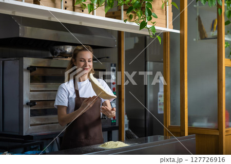 Female cooker preparing dough for pizza in the kitchen Female cooker preparing dough for pizza in the kitchen 127726916