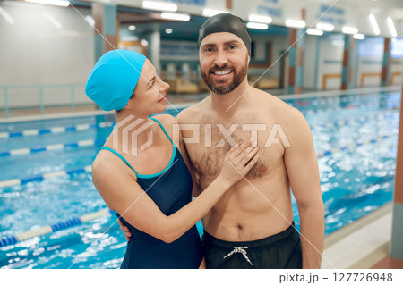 Young cute couple in swimwear in the swimming pool looking happy Young cute couple in swimwear in the swimming pool looking happy 127726948