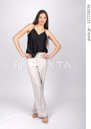 Beautiful woman with black blouse and white pants studio portrait Beautiful woman with black blouse and white pants studio portrait 127728256