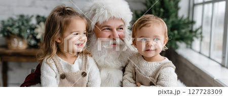 Santa Claus shares a joyful moment with two children in a festive setting, capturing the spirit of Christmas with smiles and laughter 127728309