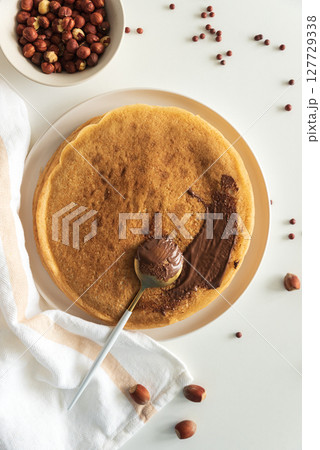 Crepes with chocolate hazelnut spread, strawberries and hazelnuts on a white wooden table. Top view Crepes with chocolate hazelnut spread, strawberries and hazelnuts on a white wooden table. Top view 127729338