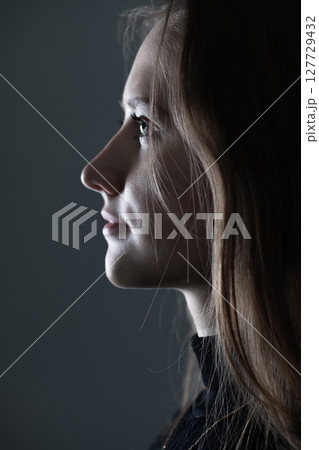 Low light side view of woman studio portrait Low light side view of woman studio portrait 127729432