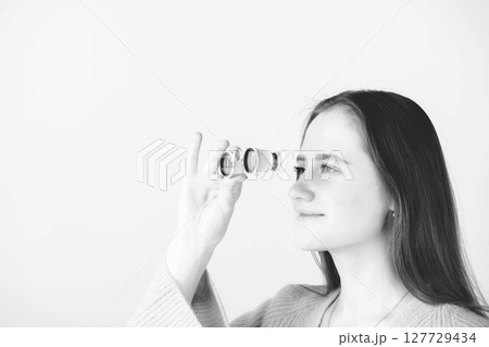 Portrait of beautiful woman watching through binoculars 127729434