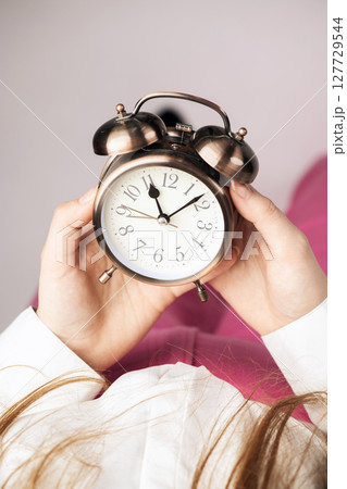 Top view of woman holding retro clock in her hands Top view of woman holding retro clock in her hands 127729544
