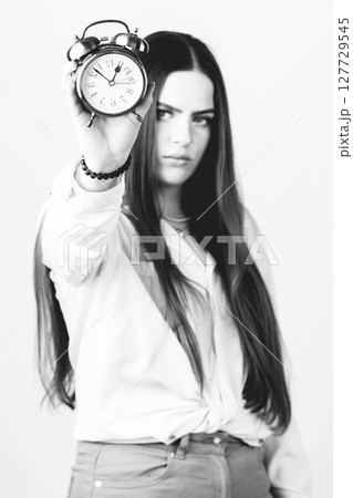 Woman with serious face showing retro clock 127729545