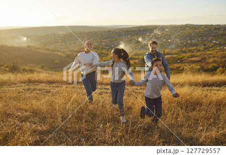 Mother, father with children running outdoors in the field at sunset Mother, father with children running outdoors in the field at sunset 127729557