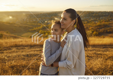 Happy smiling mother standing in the field with child daughter outdoor. Happy smiling mother standing in the field with child daughter outdoor. 127729735