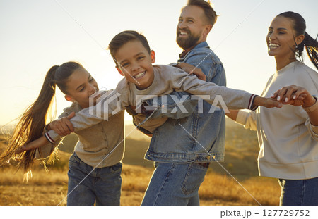 Happy young family of four with two kids having fun in the field at sunset. Happy young family of four with two kids having fun in the field at sunset. 127729752