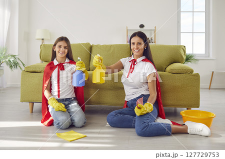 Happy smiling mother with child daughter in super heroes costumes cleaning floor at home. Happy smiling mother with child daughter in super heroes costumes cleaning floor at home. 127729753
