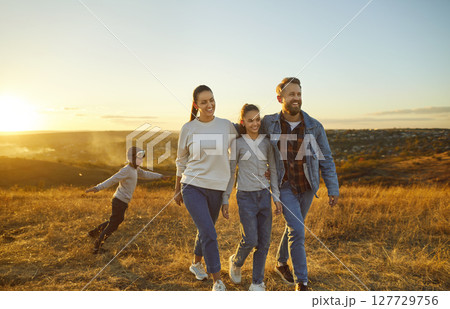 Happy family with kids walking in the field together enjoying nature outdoors. Happy family with kids walking in the field together enjoying nature outdoors. 127729756