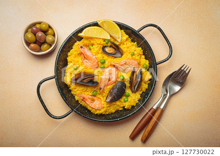 Spanish seafood Paella with shrimps, mussels, peas and lemon in a pan on light beige background top view Spanish seafood Paella with shrimps, mussels, peas and lemon in a pan on light beige background top view 127730022